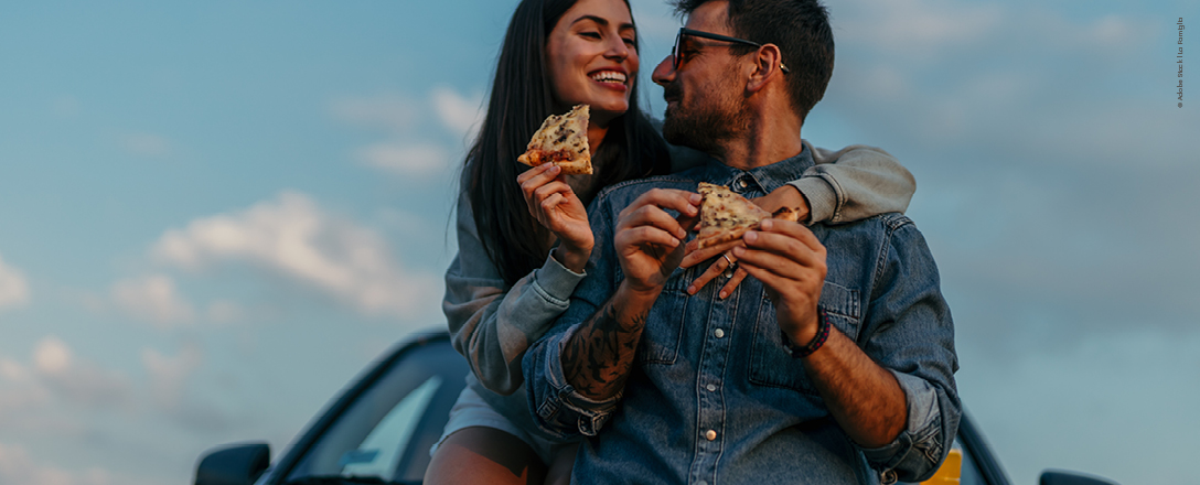 Mann und Frauen essen beim gemeinsamen Roadtrip Pizza